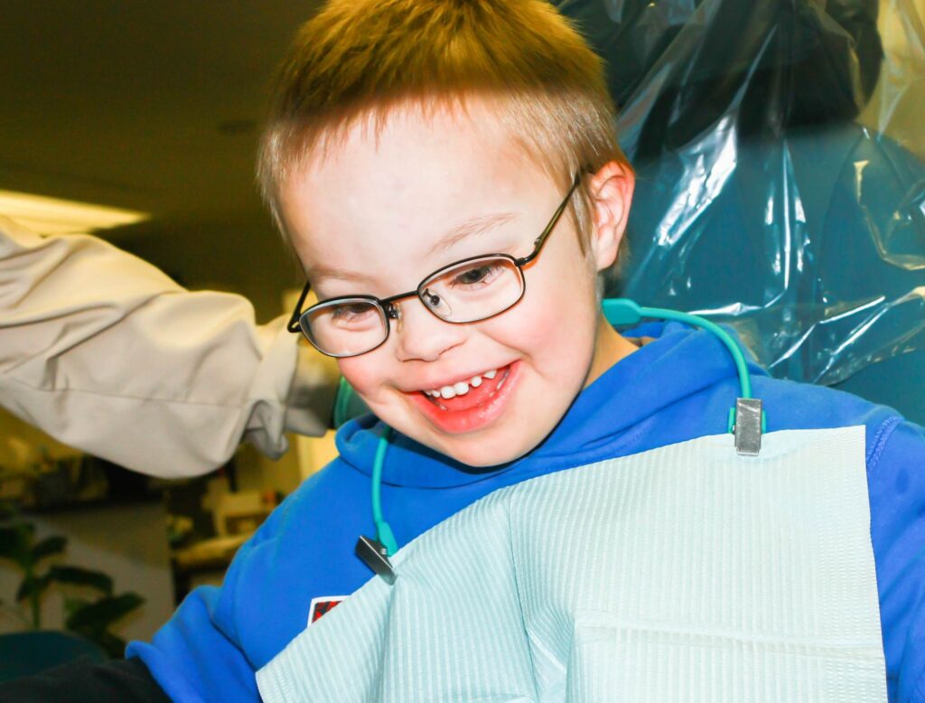 cute young boy with downs syndrome sitting in dentist chair