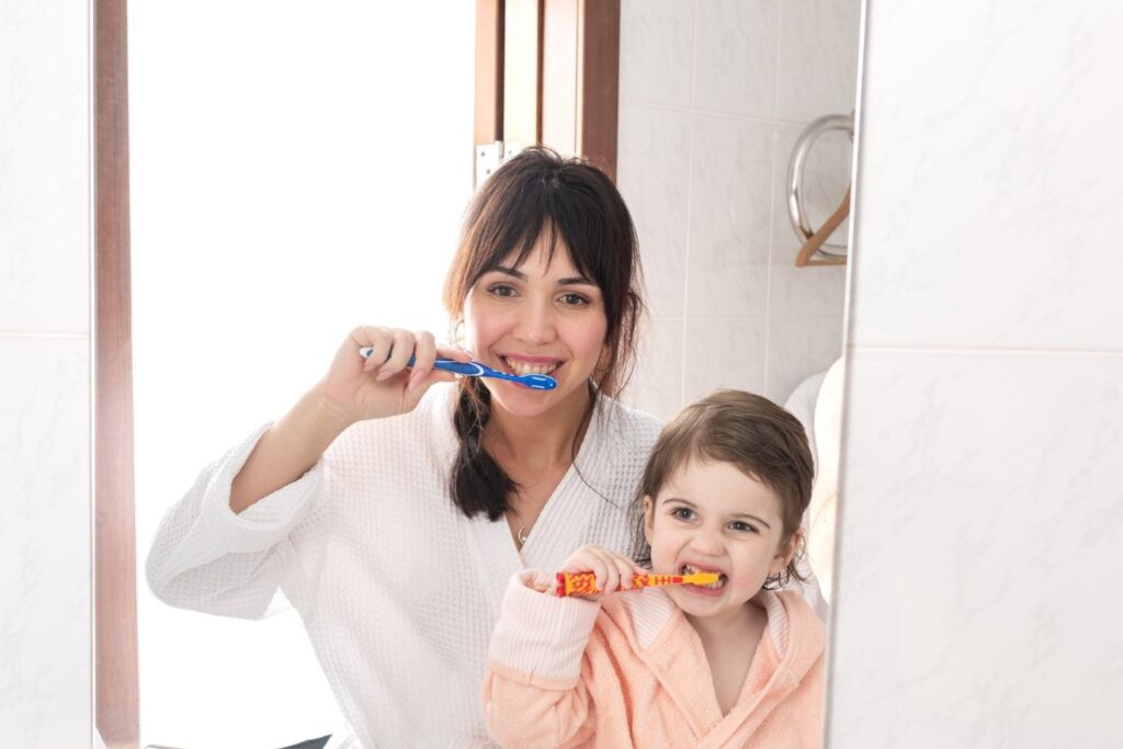 mom and daughter brushing their teeth together