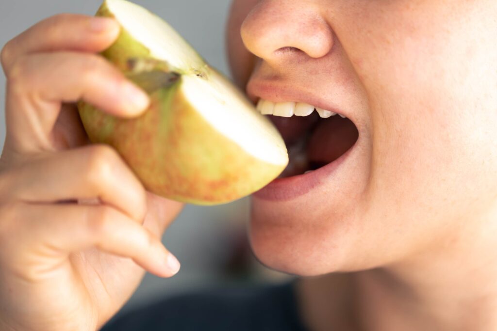 woman eats piece of fresh apple